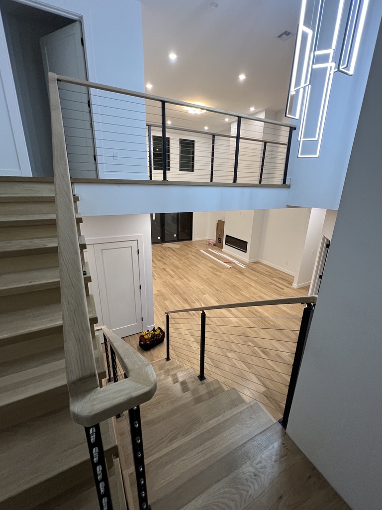 Interior stair atrium with black posts and pale hardwood handrail.