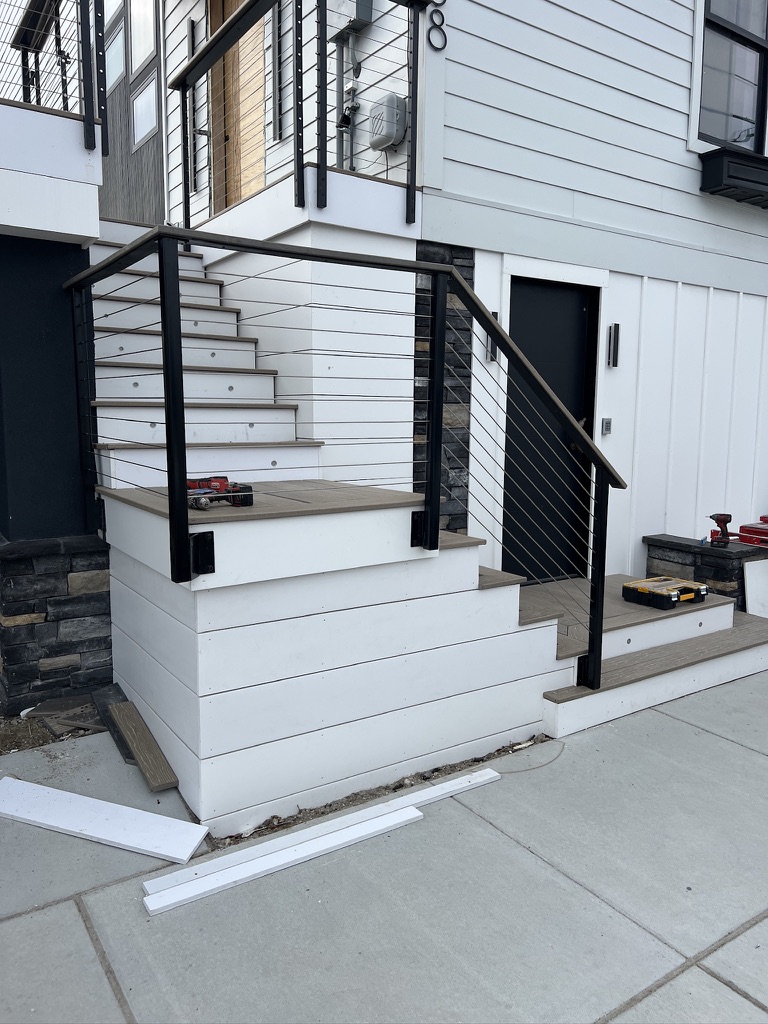 Exterior stair and landing with custom cable railing at a shore home.