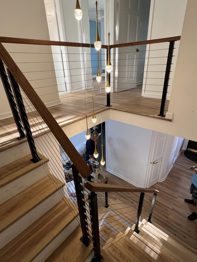 Warm wood stair landing with black cable railing.